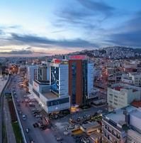 Un edificio moderno con un llamativo letrero 'ANEMON', rodeado de una concurrida calle urbana y edificios residenciales.
