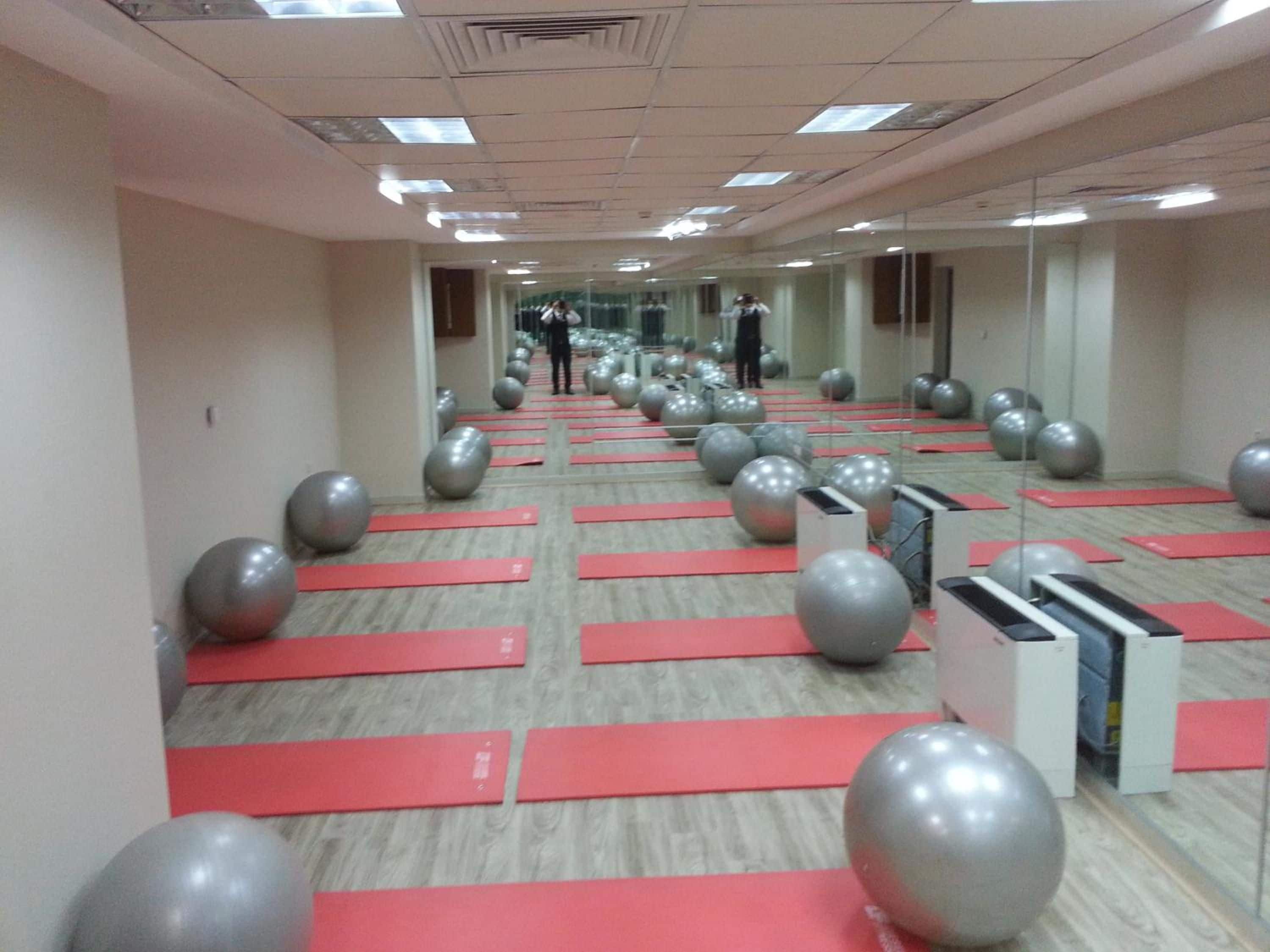 Een fitnessruimte met oefenballen en rode matten, netjes opgesteld.