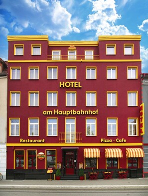 Um edifício vermelho e amarelo com uma placa que diz "HOTEL am Hauptbahnhof".