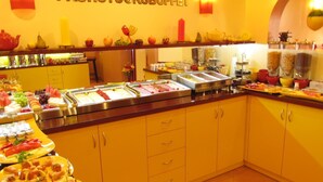 A buffet area with various food items and a sign that reads "FRÜHSTÜCKBUFFET". - Hotel am Hauptbahnhof (Schwerin)