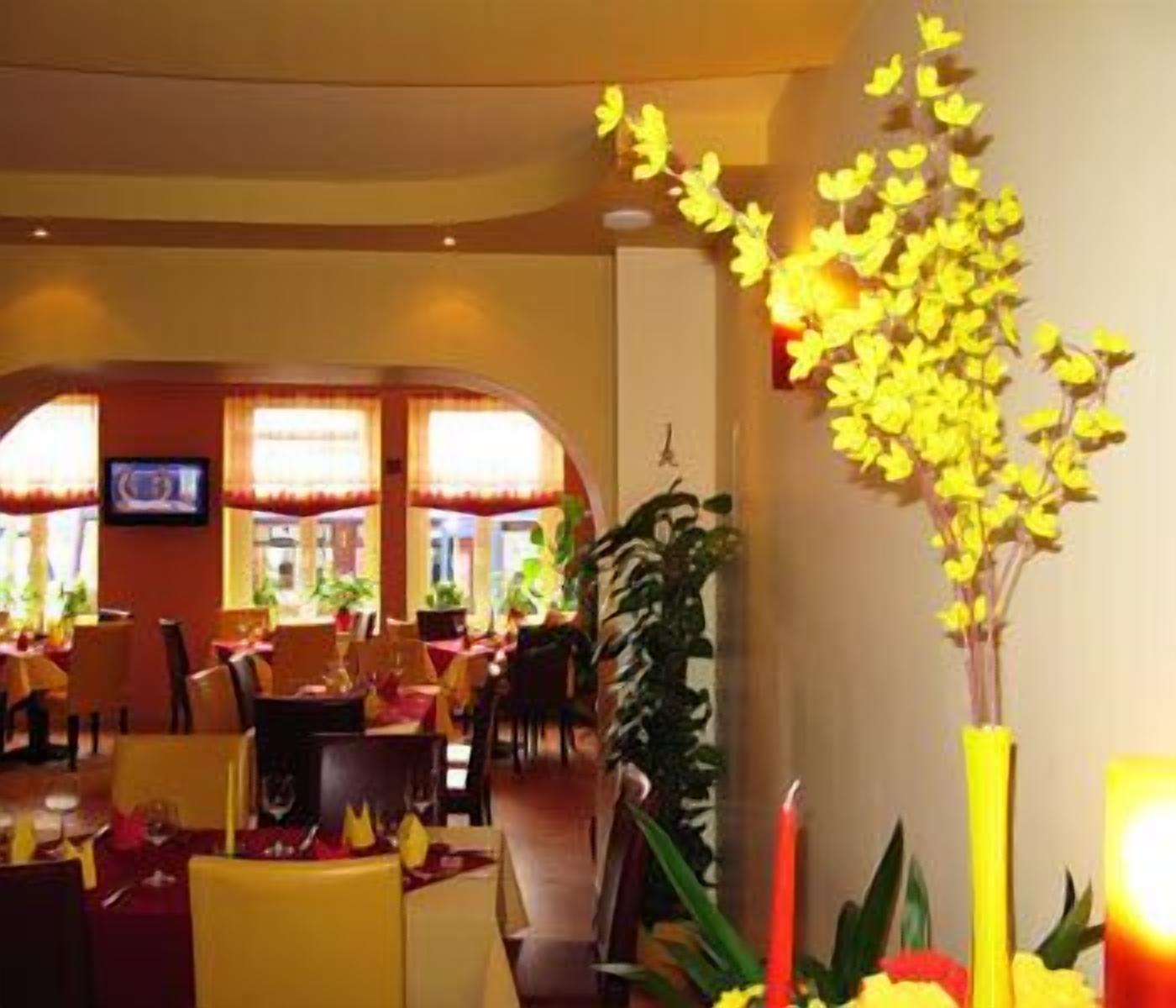 Un restaurante con sillas amarillas, un televisor en la pared y un arreglo floral amarillo.