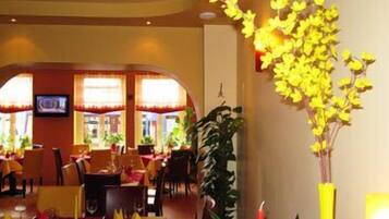 Un restaurante con sillas amarillas, un televisor en la pared y un arreglo floral amarillo.