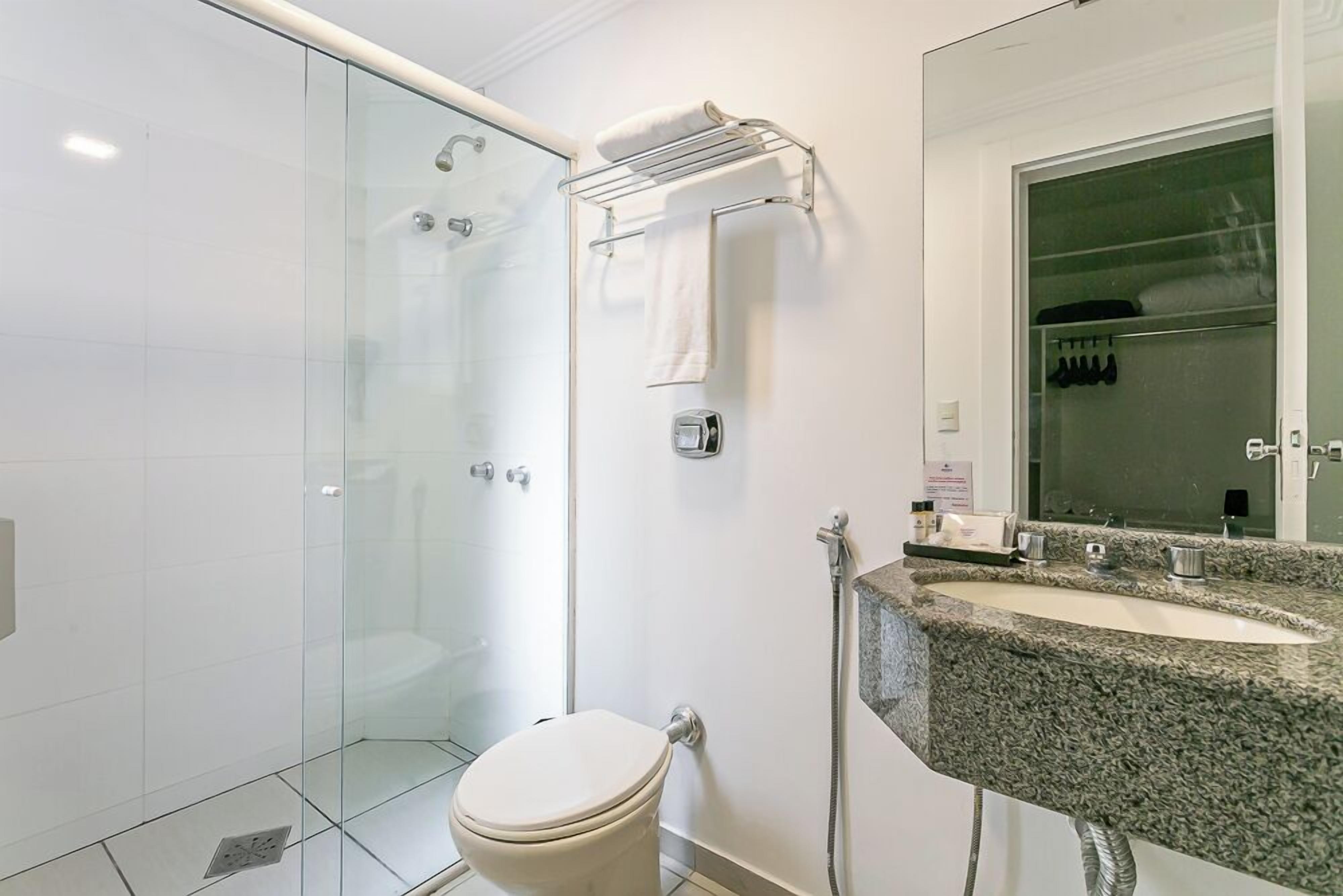 Une salle de bain moderne avec une douche à parois de verre, des toilettes, un lavabo en granit et un porte-serviettes.