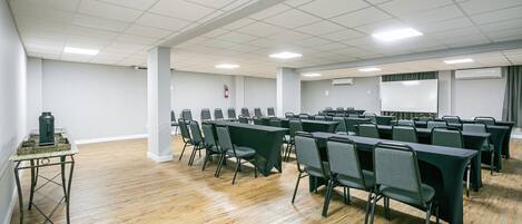 Un salón de conferencias con una larga mesa y sillas, una mesa pequeña con una lámpara, y una pizarra.