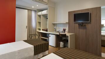 A hotel room with two beds, a desk, a television, and a mini-fridge.