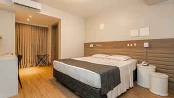 Una habitación de hotel moderna con una cama grande, mesitas de noche, un escritorio y un aire acondicionado.