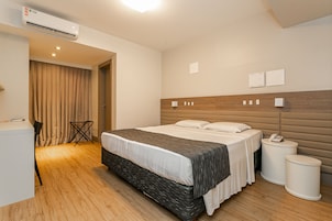 Una camera d'albergo moderna con un letto grande, comodini, una scrivania e un condizionatore.