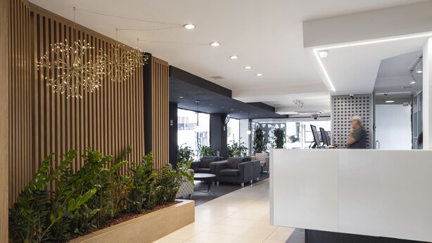 Una moderna zona de recepción con un revestimiento de madera, mostrador de recepción y asientos.