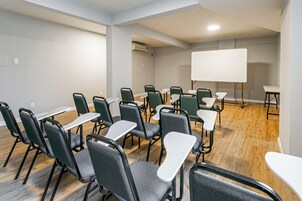Una sala conferenze con diversi tavoli e sedie, una lavagna e un condizionatore d'aria a parete.