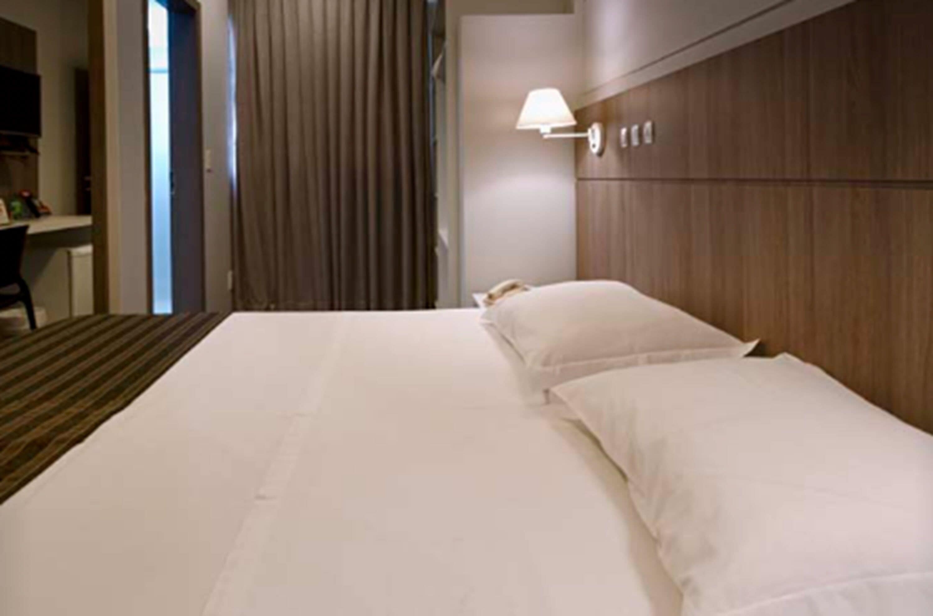 Une chambre d’hôtel avec un grand lit, une lampe de chevet et une tête de lit en bois.