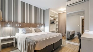 Una habitación de hotel moderna con una cama grande, mesitas de noche, un armario y un escritorio.
