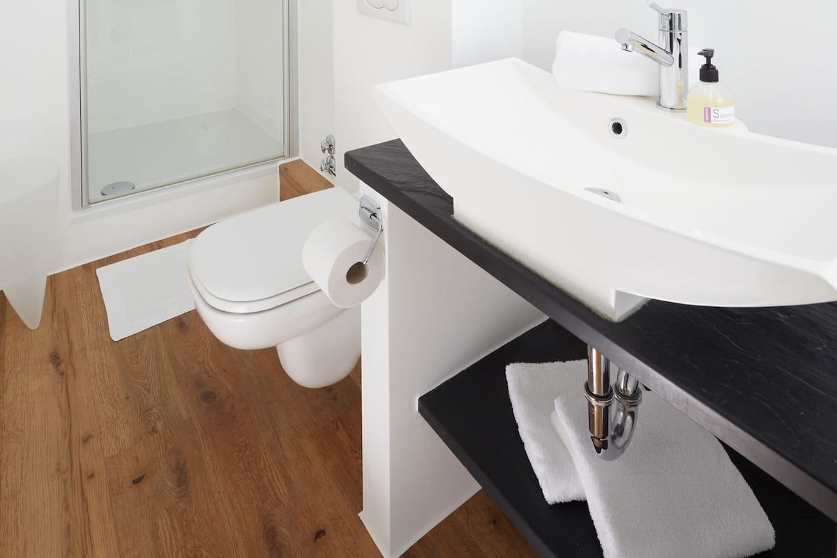 Un baño moderno con cabina de ducha de vidrio, un lavabo blanco y un espejo grande.