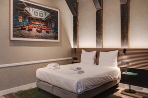 Habitació d'hotel amb un llit, un quadre i un capçal de fusta.