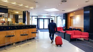 A modern lobby with a bar area, seating, and a clear exit sign.