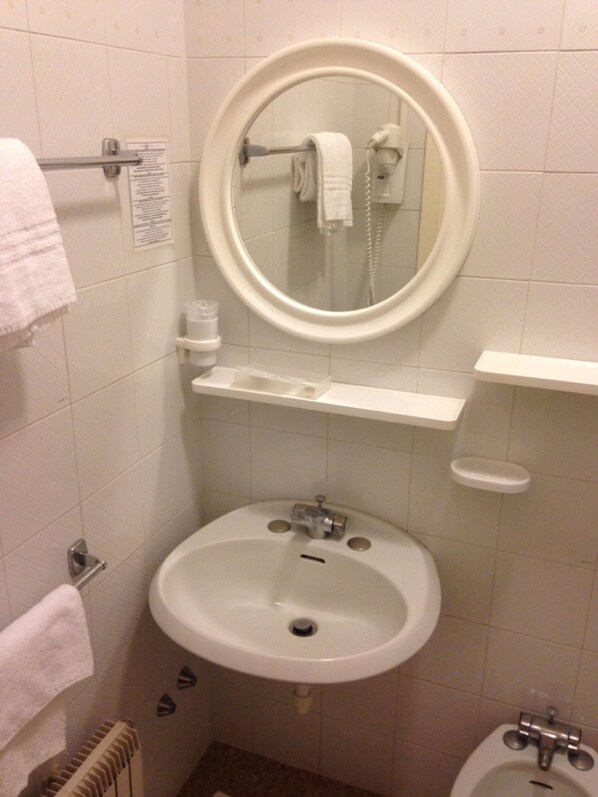 A bathroom with a sink, a mirror, a towel rack, and a toilet.