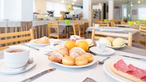 A breakfast setting with pastries, fruits, and a plate of salami.