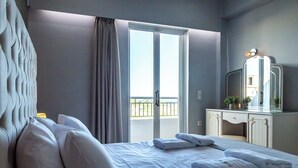 A hotel room with a bed, a bedside table with books, a dresser with a mirror, and a balcony with curtains. - Zante Pantheon Hotel (Zakynthos)