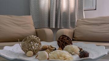 Un piatto bianco con decorazioni su un tavolo in un soggiorno con divani color beige e una tenda a motivi.