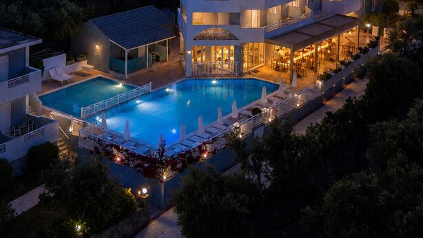A multi-story hotel with a swimming pool, outdoor seating, and a view of the surrounding landscape. - Zante Pantheon Hotel (Zakynthos)