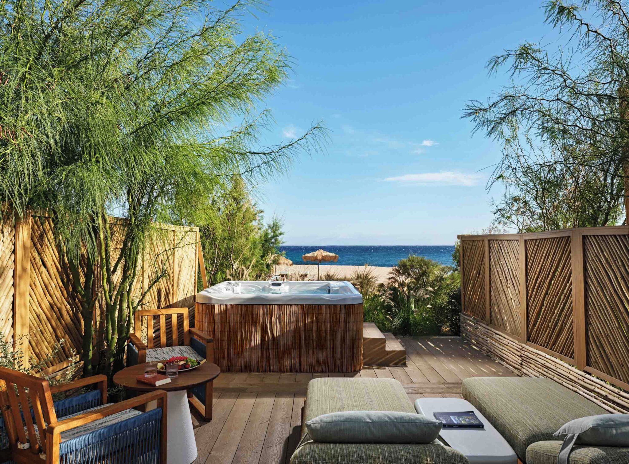 A wooden deck with a hot tub, seating area, and a view of the sea.