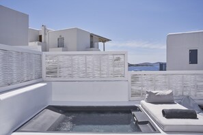 Terraço no telhado com hidromassagem, paredes brancas e vista para o mar.