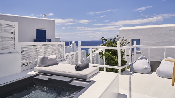 A rooftop terrace with a hot tub, white walls, and a view of the sea. - Boho Suites (Mykonos)