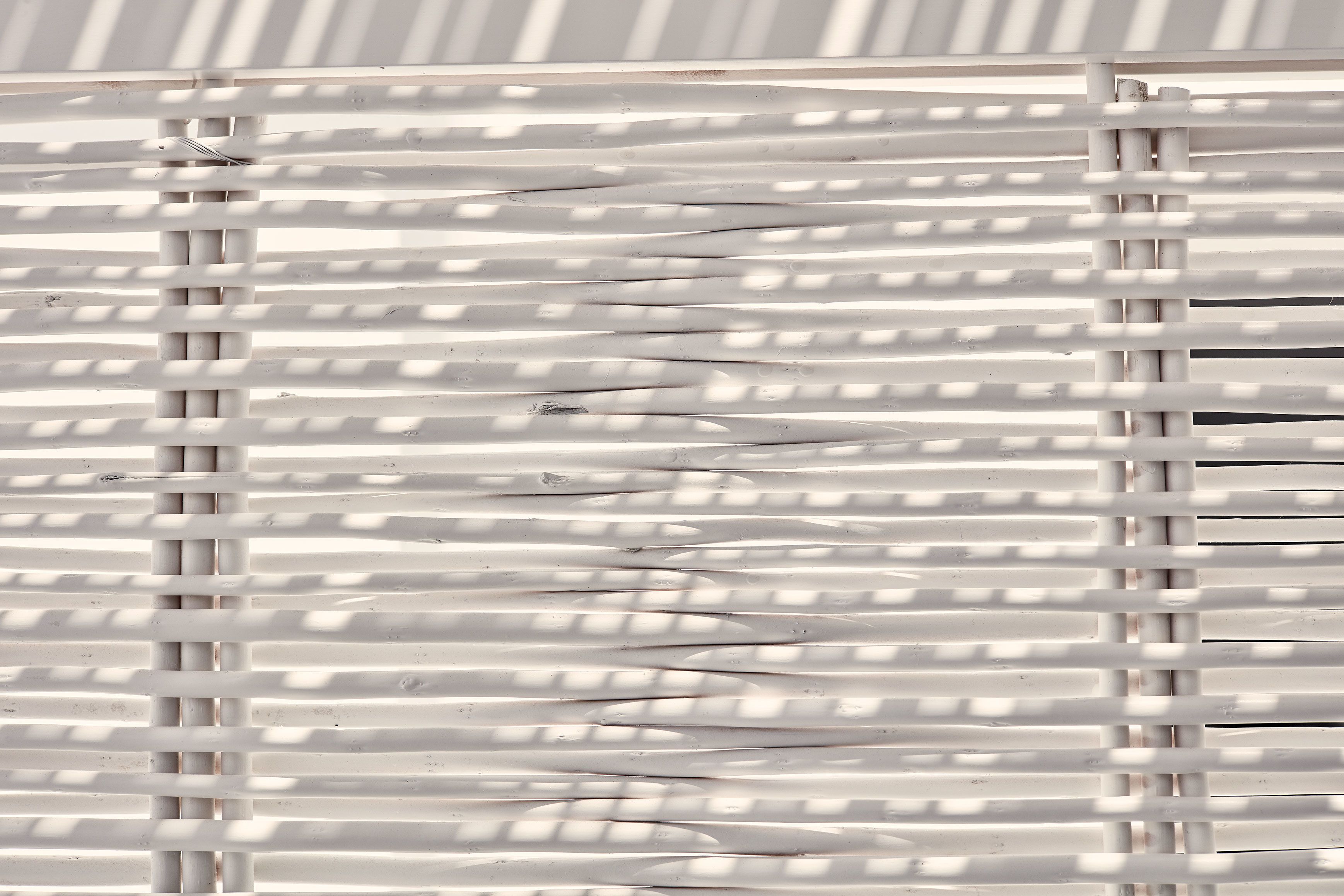 A close-up of a white, horizontal slatted structure, possibly part of a window or partition.
