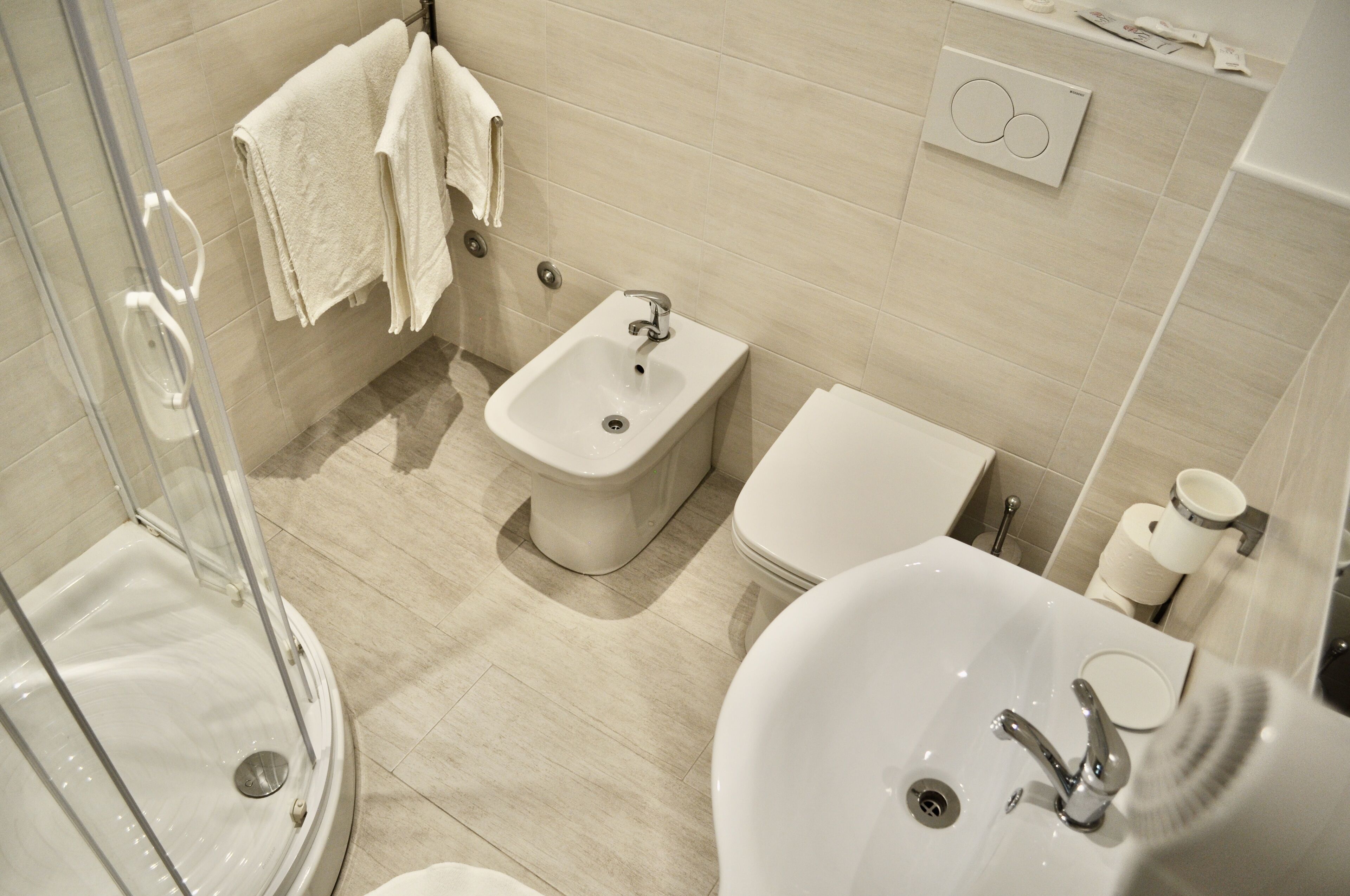A modern bathroom with a glass-enclosed shower, a bidet, a toilet, and a sink.