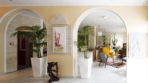 Un hall d’entrée spacieux, doté de hauts plafonds, d’arcades et de grandes plantes en pot.