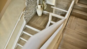 Un escalier en bois avec des rampes blanches et un vase blanc posé sur la plateforme.