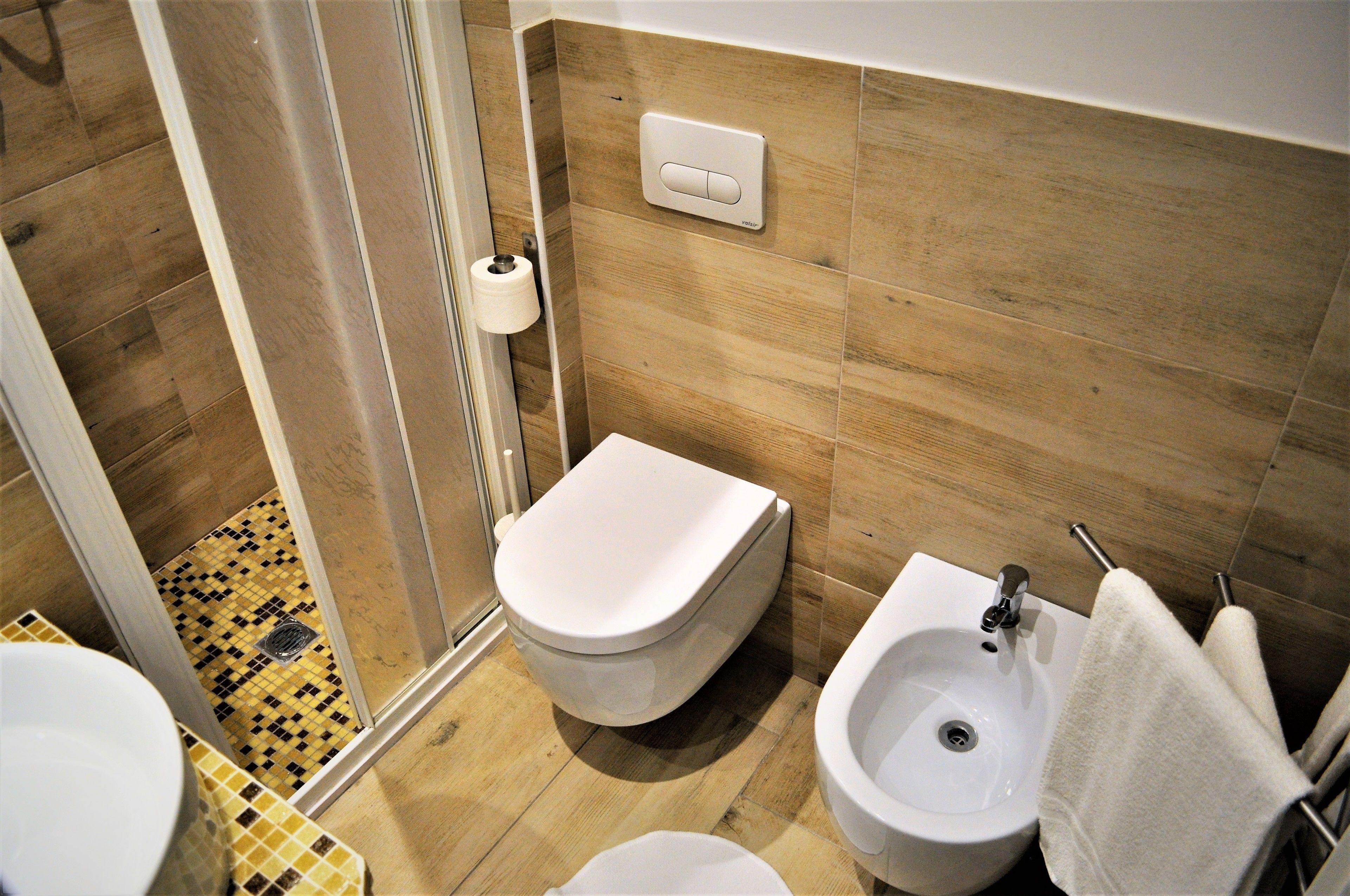 A bathroom with a toilet, bidet, sink, and a towel rack.
