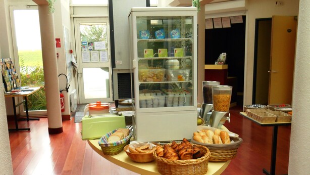 A buffet setup with various food items, a refrigerator, and a coffee machine. - Good Night Hôtel (Arques)