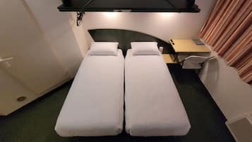 A twin bed room with a desk and chair, a small table, and a curtain.