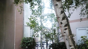 A tree in a courtyard with a building in the background. - Good Night Hôtel (Arques)