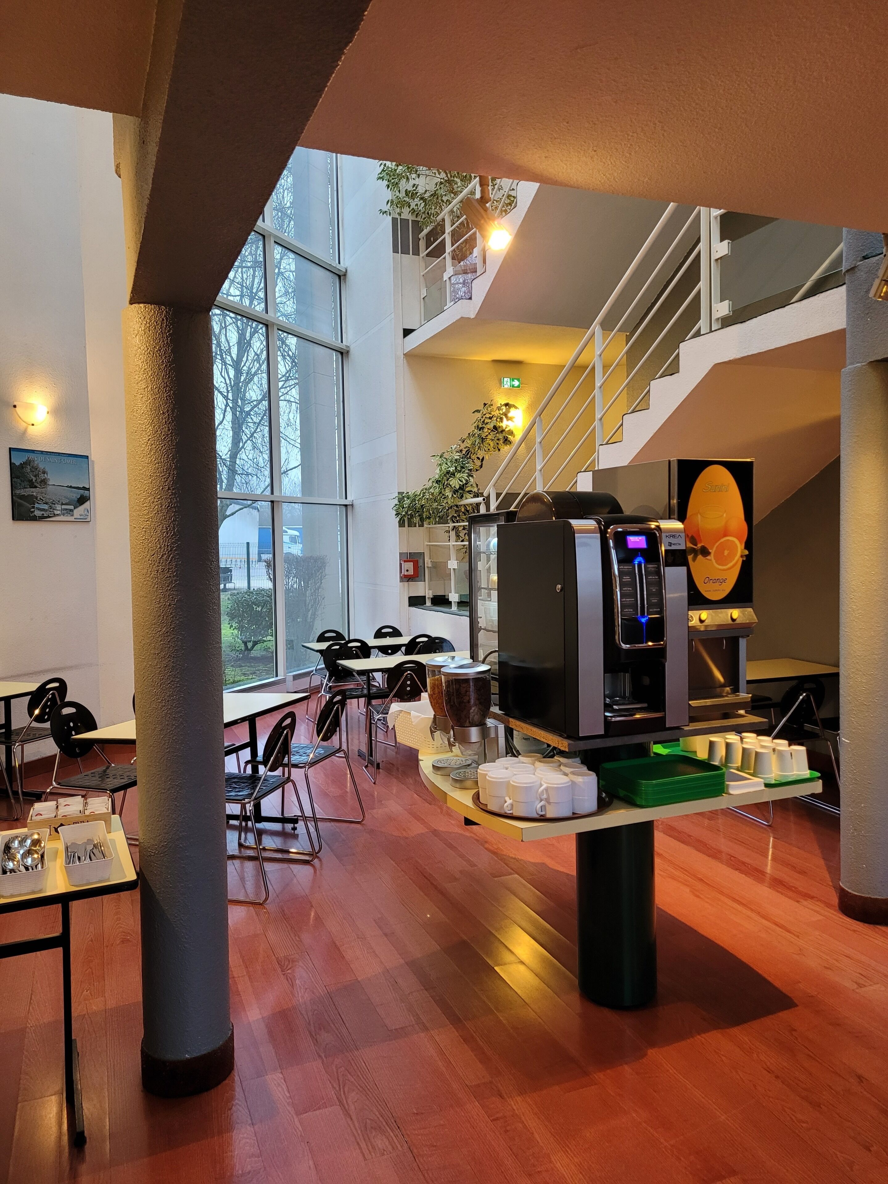 A modern interior with a coffee machine, seating area, and a staircase.