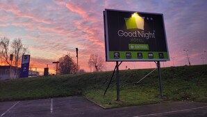 A billboard advertising a hotel with amenities such as Wi-Fi, individual WC, and 24-hour service. - Good Night Hôtel (Arques)