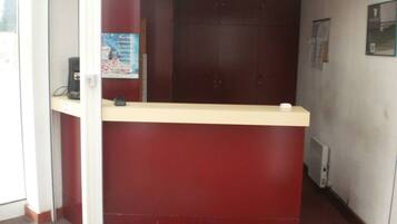 A reception desk with a red counter and a small black device on it.