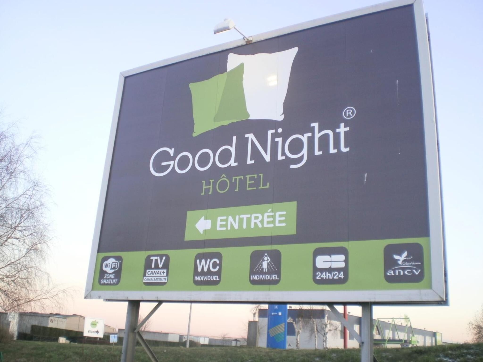 A billboard for Good Night Hotel with amenities including Wi-Fi, TV, individual WC, and 24-hour service.