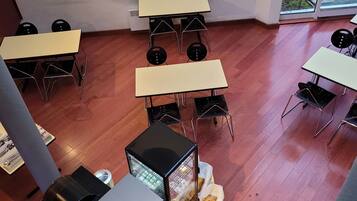 Ein Essbereich mit Tischen und Stühlen, einer Grillstation und Blick durch die Glastür.