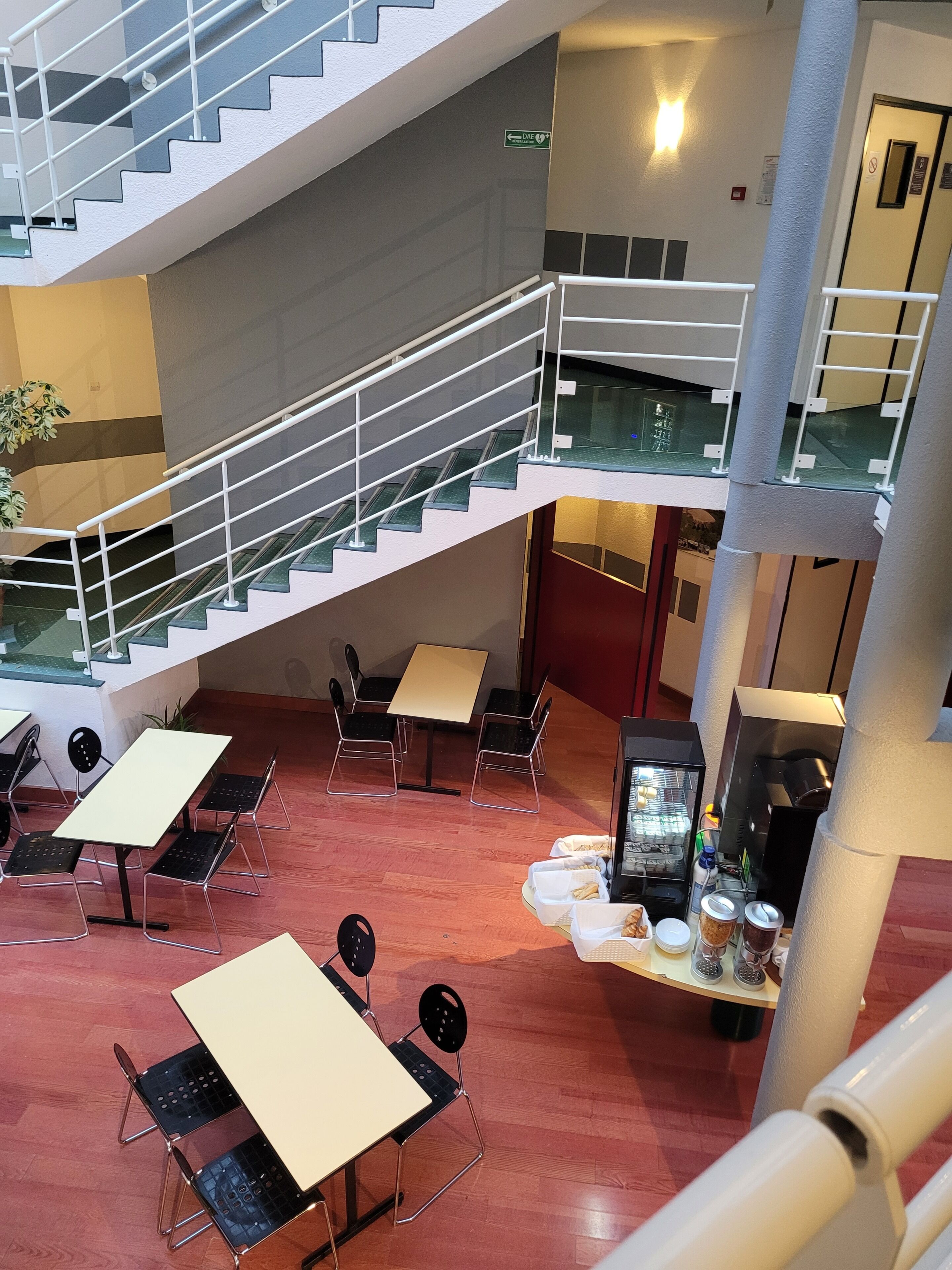 A multi-level indoor space with a staircase, seating area, and a coffee machine.