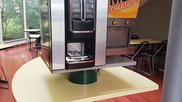 A coffee machine with a 'MEL ORANGE' label, a glass display, and a menu above it.
