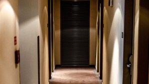A hotel hallway with a carpeted floor, doors on both sides, and an emergency exit sign above a door. - Royal Park Boutique Hotel (Budapest)