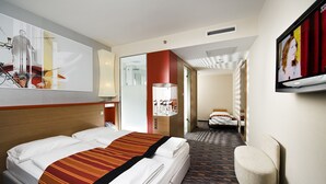A hotel room with a large bed, a chair, a TV, and a bathroom visible through an open door. - Royal Park Boutique Hotel (Budapest)