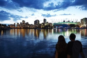 A city skyline at dusk with a couple facing the waterfront. - The Burrard (Vancouver)