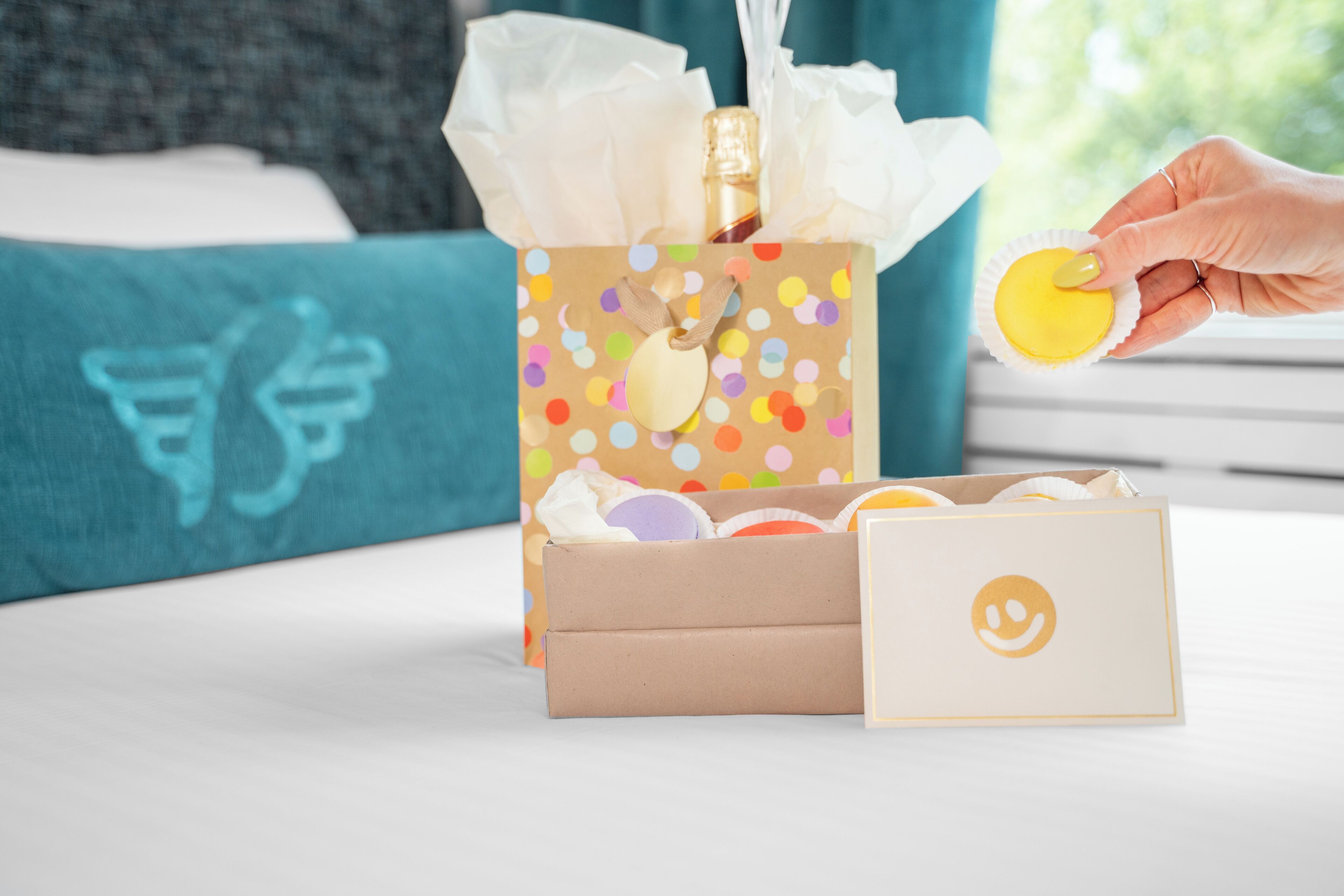 A gift box with colorful polka dots and a smiley face label, placed on a white surface.