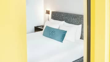 Quarto de hotel com uma cama, mesa de cabeceira e abajur. O número "421" está na parede.
