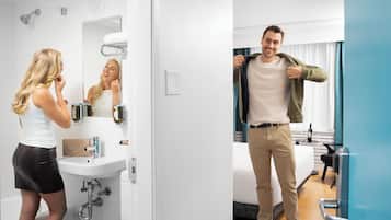 A hotel bathroom with a sink, mirror, and towel rack.
