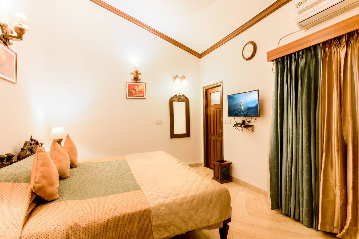 Une chambre d’hôtel avec un lit, une télévision, une horloge et une fenêtre avec des rideaux.