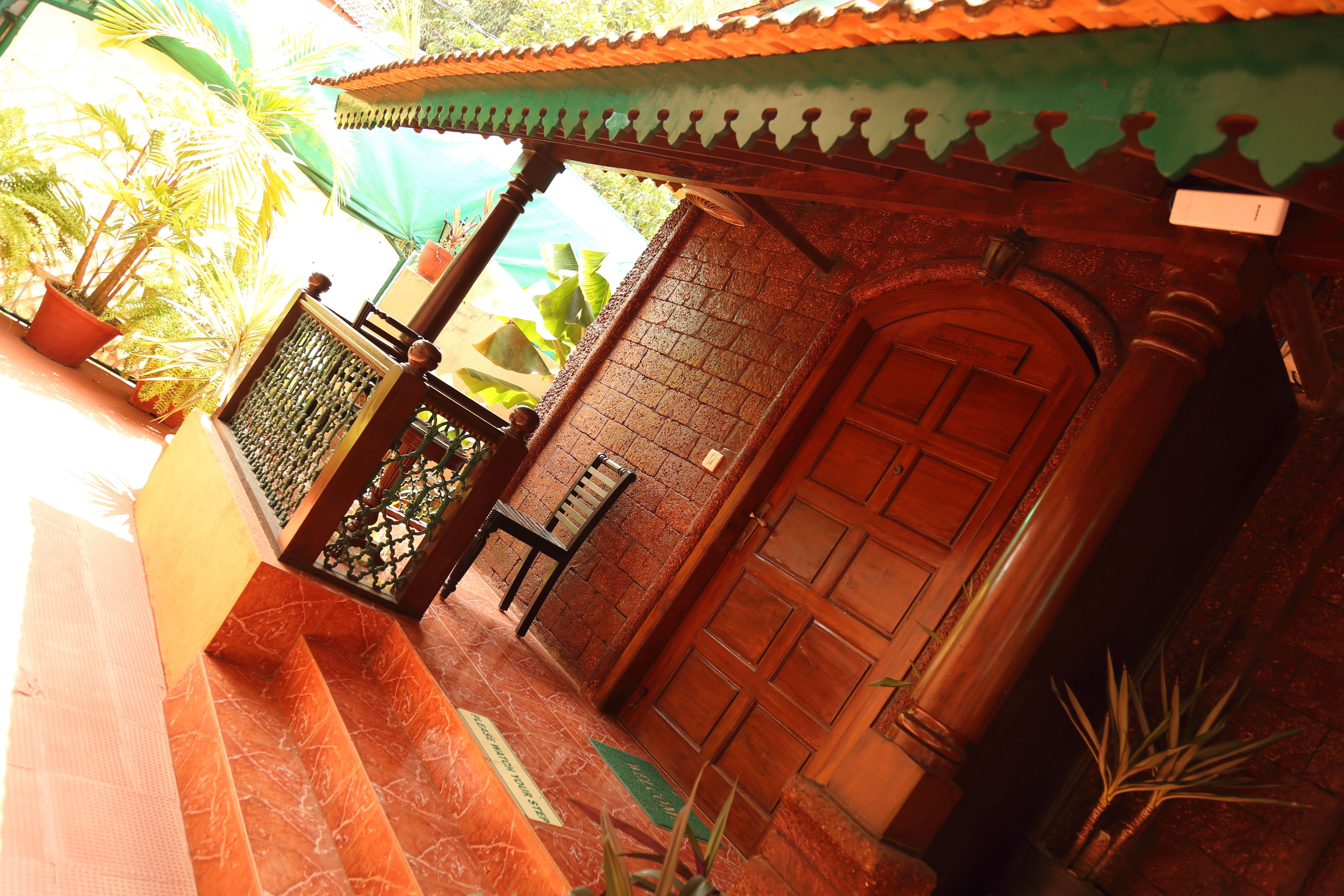A traditional building with a wooden door, a tiled entrance, and a small balcony with a chair.
