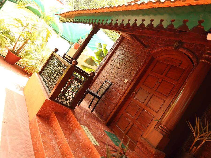 A traditional building with a wooden door, a tiled entrance, and a small balcony with a chair.